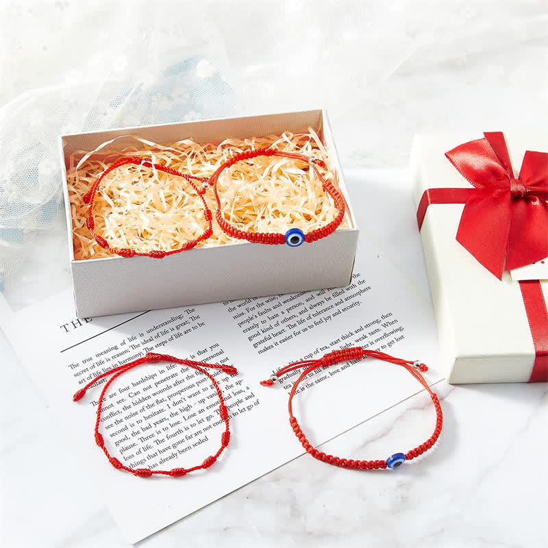 4Pcs Evil Eye Red String – Red knotted cord bracelet on white marble with green leaves, minimalist