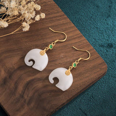 Feng Shui Elephant White Jade Fortune Earrings on wooden board with dried flowers