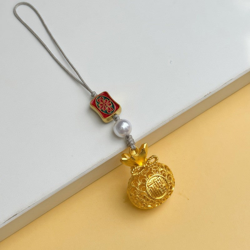 Gold Maneki Neko lucky cat ornament with peace talisman and red cord on white fabric