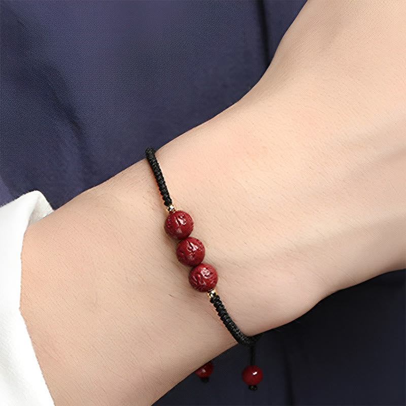 Cinnabar Om Mani Padme Hum Braided Bracelet – Black cord with carved red beads on wrist, cinnabar jewelry