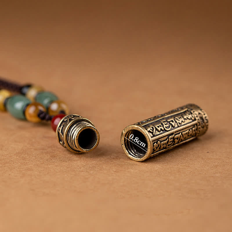 Antique brass cylindrical locket pendant necklace showing screw-top opening, engraved Tibetan script, multi-colored gemstone beads on brown cord