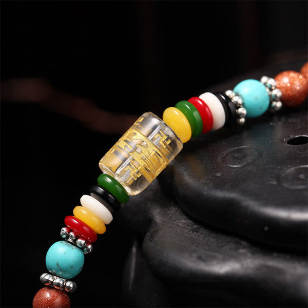 Goldstone Mala Bracelet – macro close-up of mantra cylinder bead and multicolor accent discs