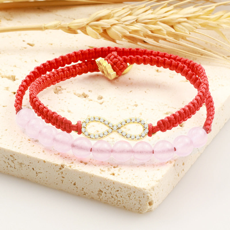 Tibetan Lotus Pink Crystal Red String Bracelet - red cord and rose quartz beads on stone slab, natural lifestyle setting