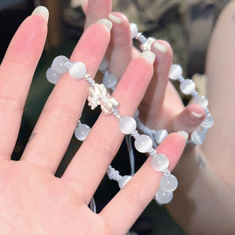 Cat's Eye PiXiu Bracelet – Hand wearing white cat's eye PiXiu bracelet, lifestyle photo