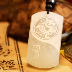White Jade PiXiu Pendant – White jade PiXiu yin-yang pendant with brown cord over ancient calligraphy scrolls