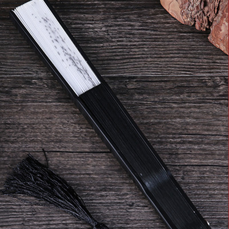Folded Fan with Tassel – Closed black fan with floral ink painting and tassel on dark wood, folding fan