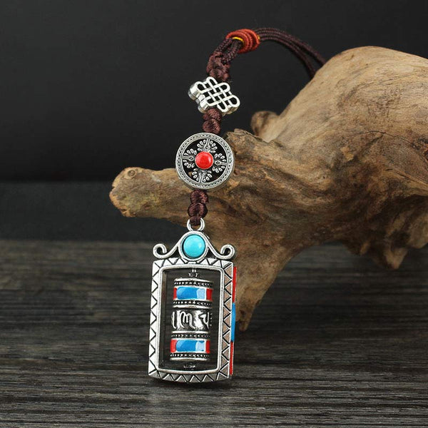 Om Mani Padme Hum Prayer Wheel Keychain – On driftwood prop with dark backdrop, moody artisan style, Buddhist pendant