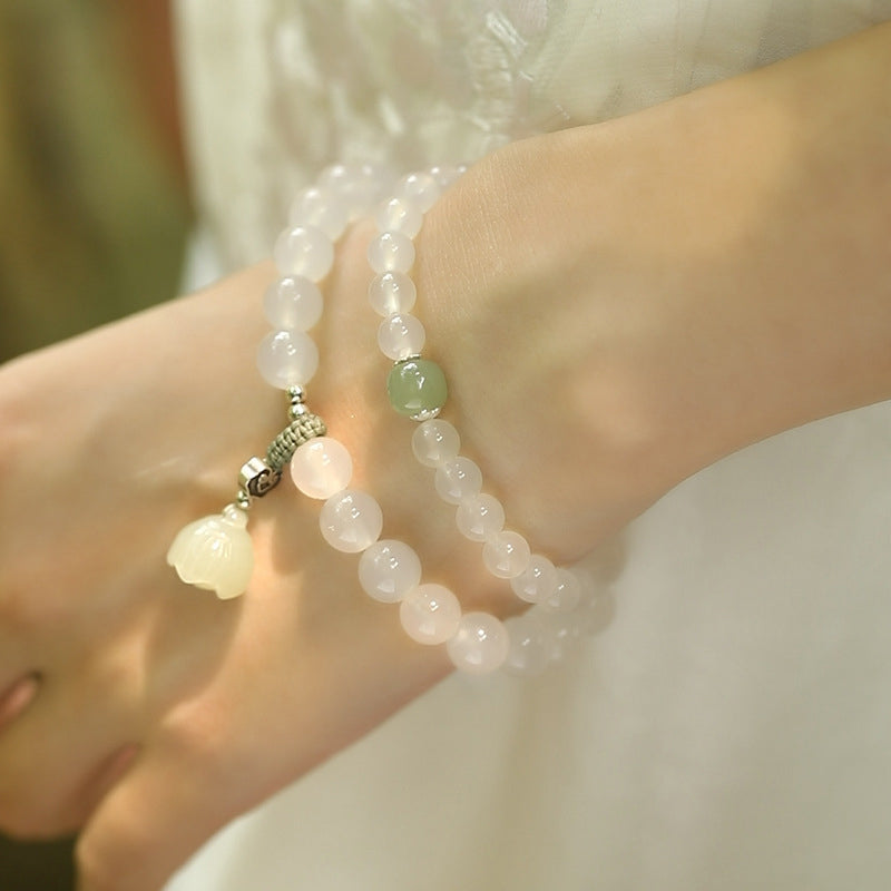 White Agate Jade Lotus Bracelet - Close-up on wrist showing carved lotus bud charm and sage green accent, jade jewelry