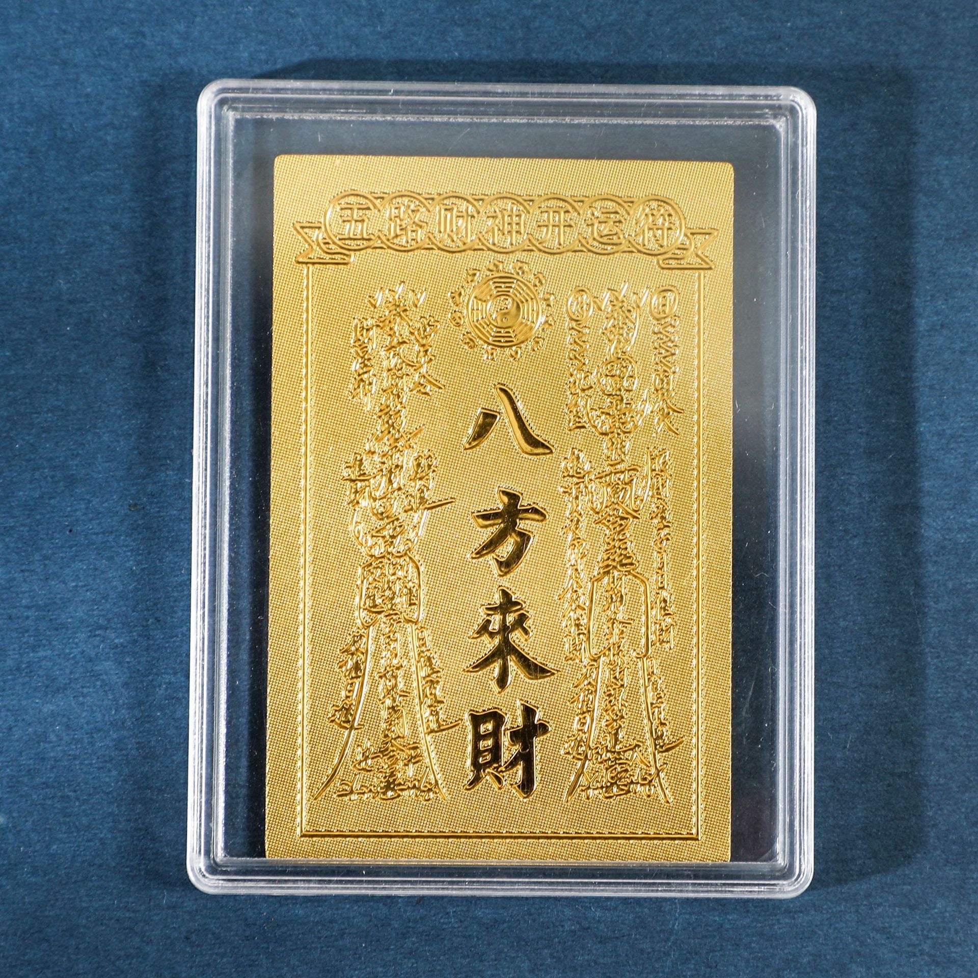Gold Wealth from All Directions sticker in clear display case on blue background
