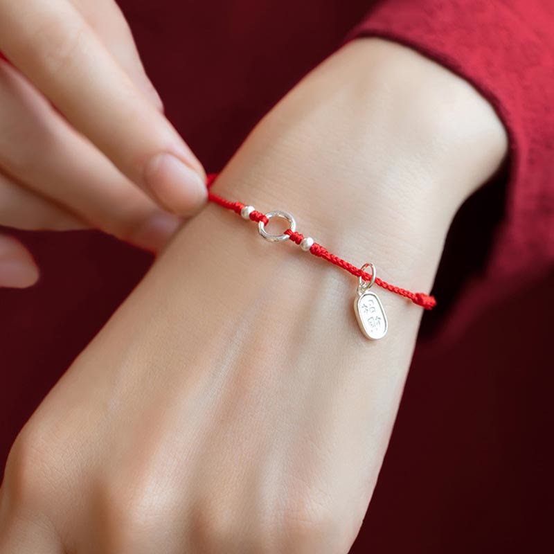 Sterling Silver Lotus Peace Buckle Red String Bracelet – Wrist shot showing the bracelet worn with silver ring, beads, and leaf charm on braided red cord over a red sleeve
