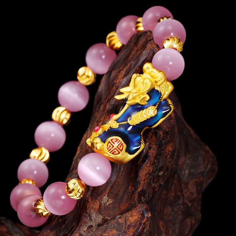 Pixiu Cat Eye Chrysoberyl Lucky Bracelet – close-up of blue and gold pi xiu on dark wood, wealth bracelet detail
