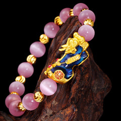 Pixiu Cat Eye Chrysoberyl Lucky Bracelet – close-up of blue and gold pi xiu on dark wood, wealth bracelet detail