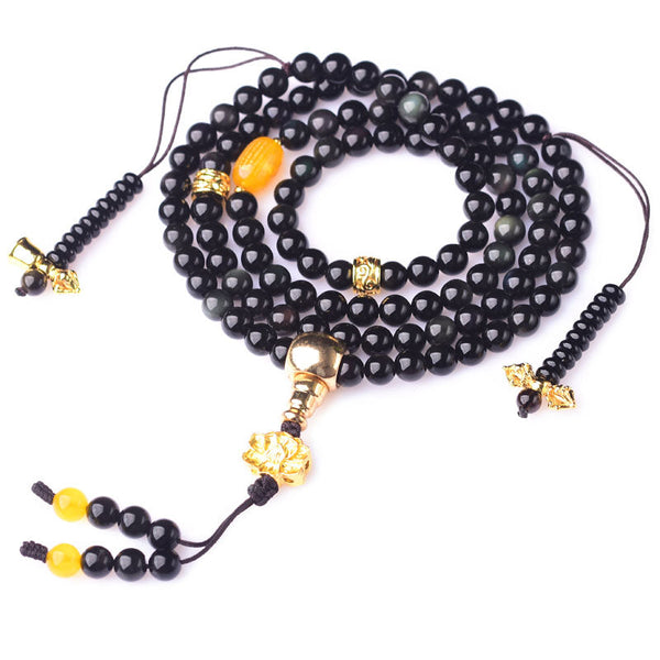 Black Obsidian Lotus Mala Bracelet - Coiled spiral on white background, gold lotus tassel visible, obsidian
