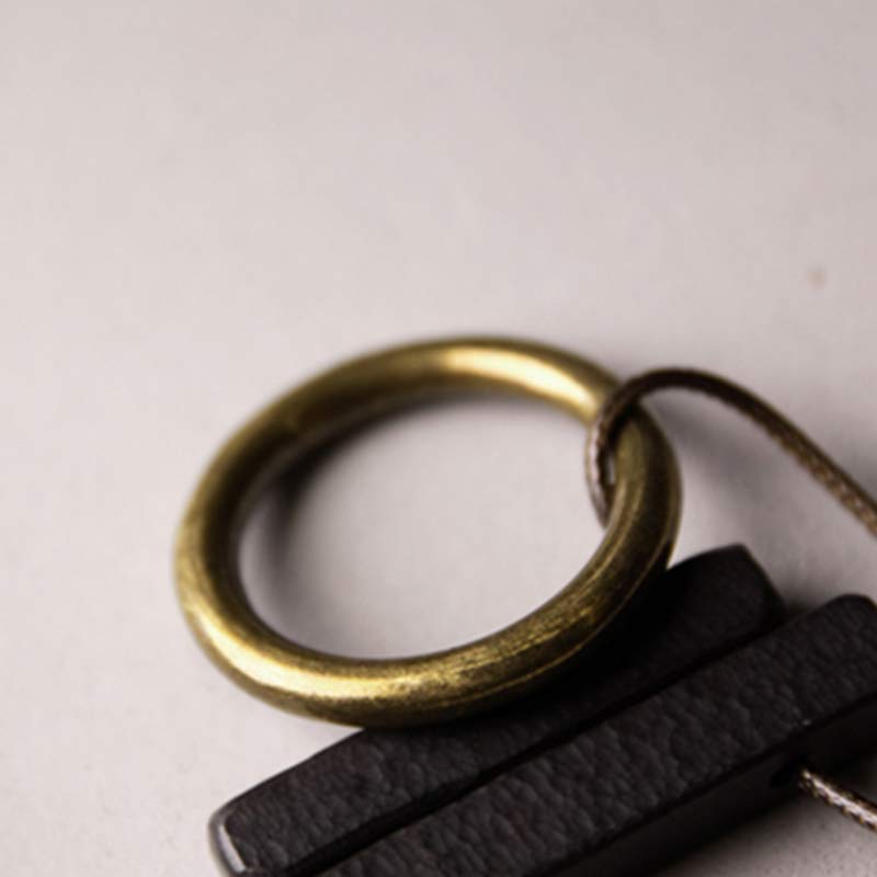Zen Circle Ebony Wood Necklace - macro detail of brass ring and leather cord, handcrafted metalwork