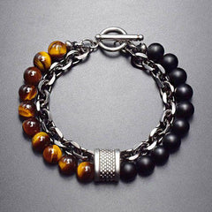 Tiger Eye Lazurite Malachite Protection Bracelet – Top-down view of men's bracelet with tiger's eye and black onyx beads, silver curb chain, textured barrel spacer, and toggle clasp on gray surface