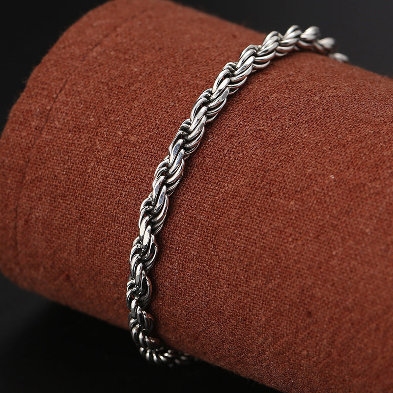 Silver Rope Bracelet – twisted chain on terracotta mandrel, dark bokeh, men's silver jewelry