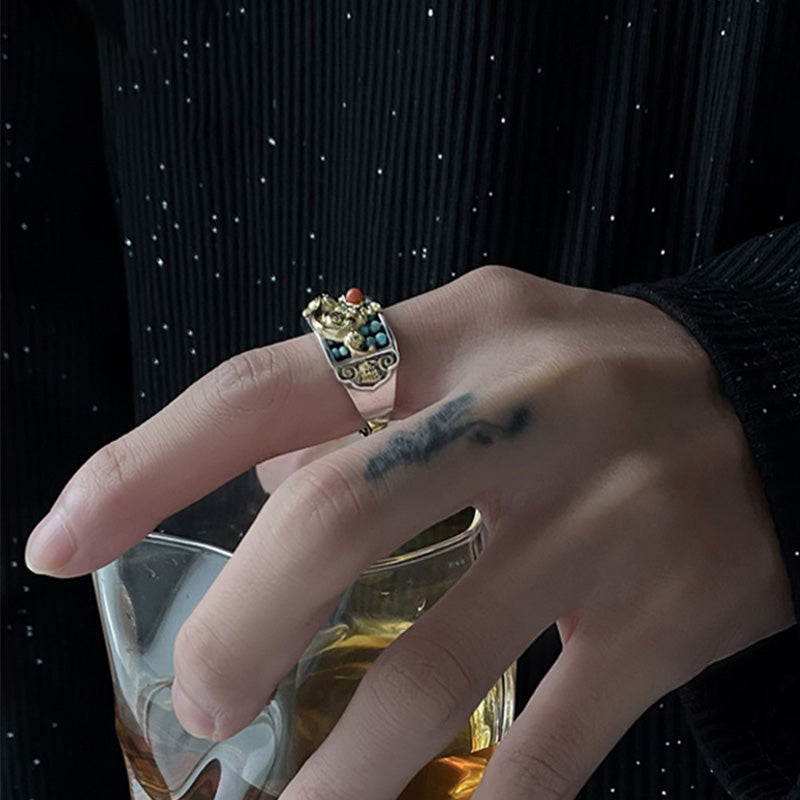 Silver PiXiu Ring – On hand holding glass with amber liquid, black background, luxury spiritual ring