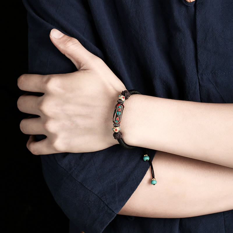 Tibetan Turquoise Om Mani Padme Hum Braided Bracelet – Black cord version worn on wrist against dark studio background
