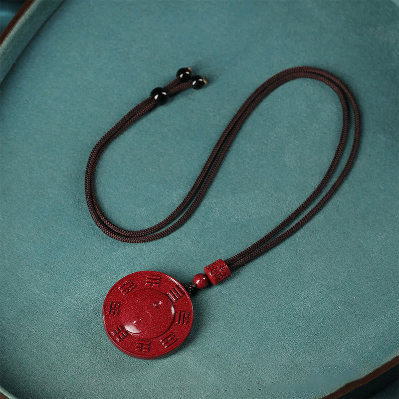 Cinnabar Yin Yang Bagua Blessing Necklace Pendant – flat lay on teal fabric, cinnabar amulet