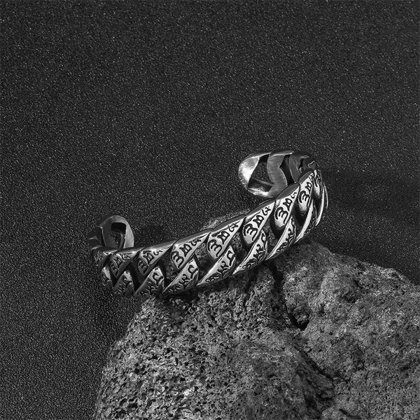 Tibetan Om Mani Padme Hum Cuff Bangle – resting on textured lava rock, engraved mantra on silver links, bold cuff