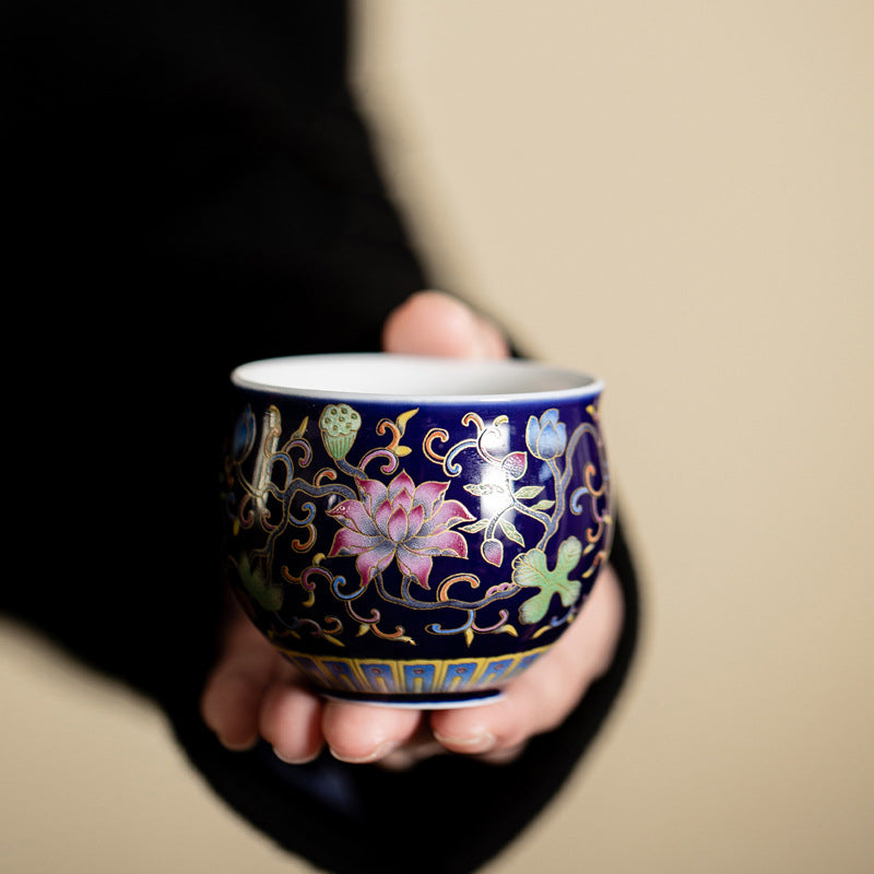 Lotus Pod Ceramic Tea Cup – deep blue lotus enamel cup tilted in hand, cobalt tea ware
