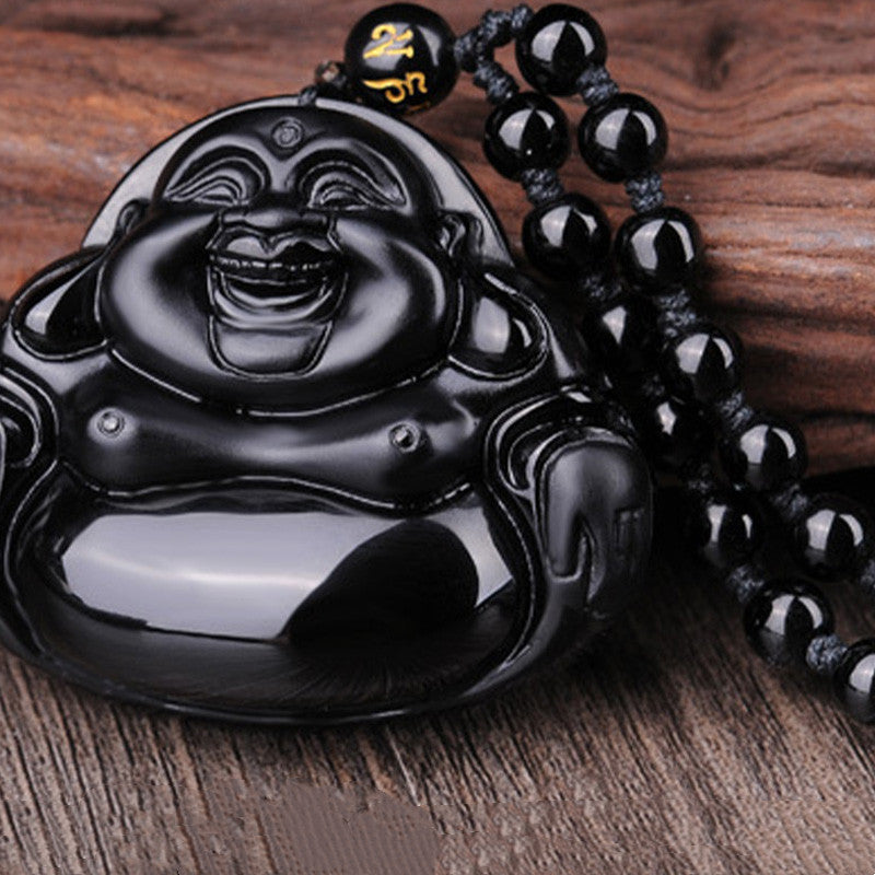 Black Obsidian Laughing Buddha Pendant – angled view with obsidian chain on rustic wood, prosperity and happiness