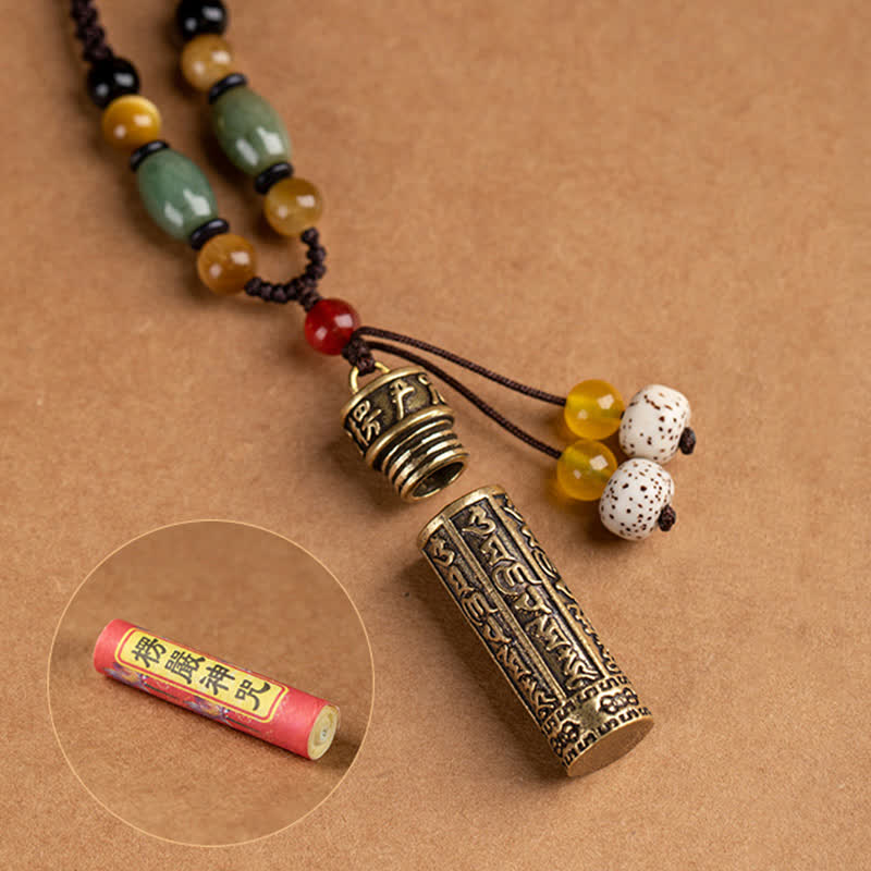 Antique brass prayer wheel pendant necklace opened revealing interior Surangama Mantra scroll, with green jade, amber, and bodhi seed beads on brown cord