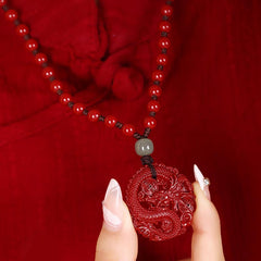 Cinnabar Hetian Jade Dragon Necklace - carved dragon pendant between fingers, openwork relief