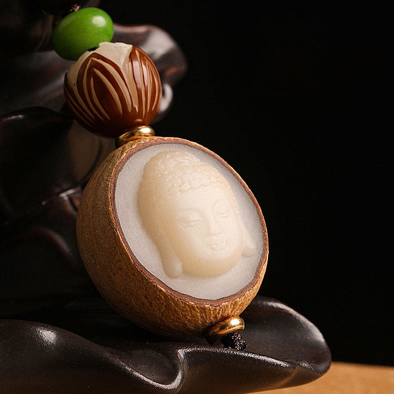 Bodhi Seed Blessing Keychain - macro detail of Buddha head carving emerging from split seed shell on dark stand, enlightenment