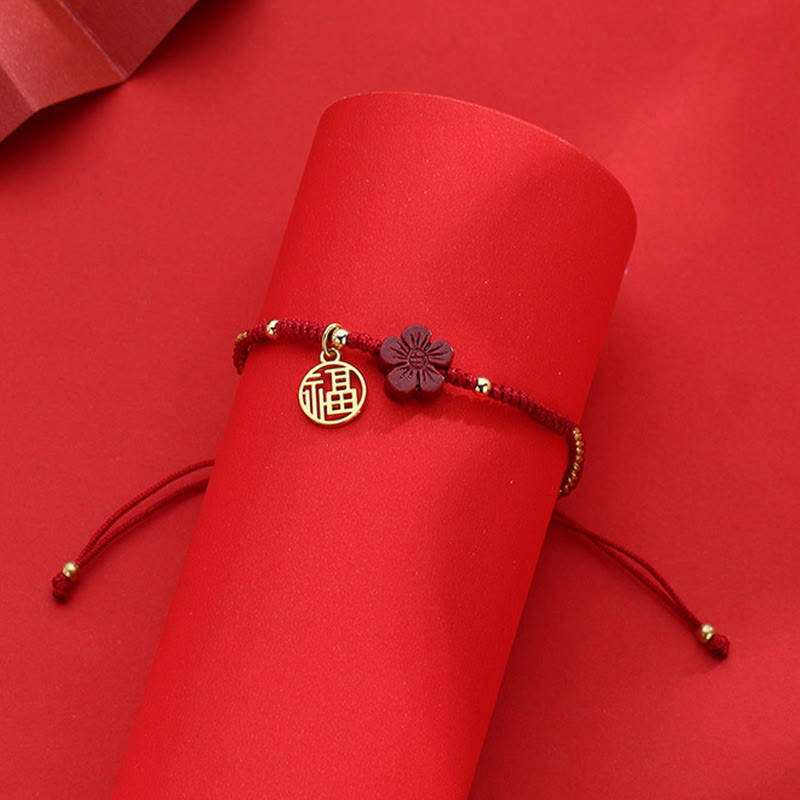 Red braided Chinese fortune bracelet with gold Fu character charm and carved flower accent, adjustable cord on velvet display stand, lucky jewelry gift