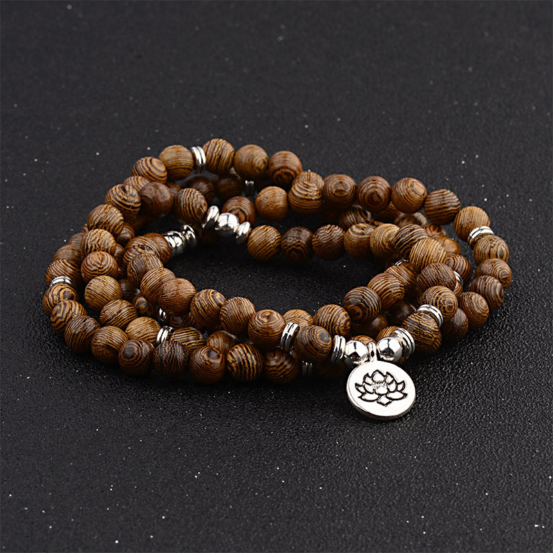 Tibetan Lightning Strike Wood Mala – triple-wrap with lotus charm on black studio surface