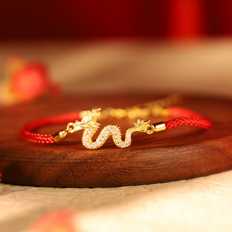 925 Silver Dragon Bracelet - Pavé dragon on red cord over dark wood, crimson bokeh, lucky charm
