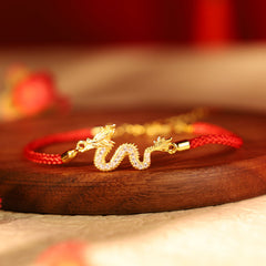 925 Silver Dragon Bracelet - Pavé dragon on red cord over dark wood, crimson bokeh, lucky charm