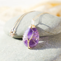 Quartz Crystal Tree of Life Necklace – amethyst pendant on gray river stones, warm bokeh, copper wire, boho