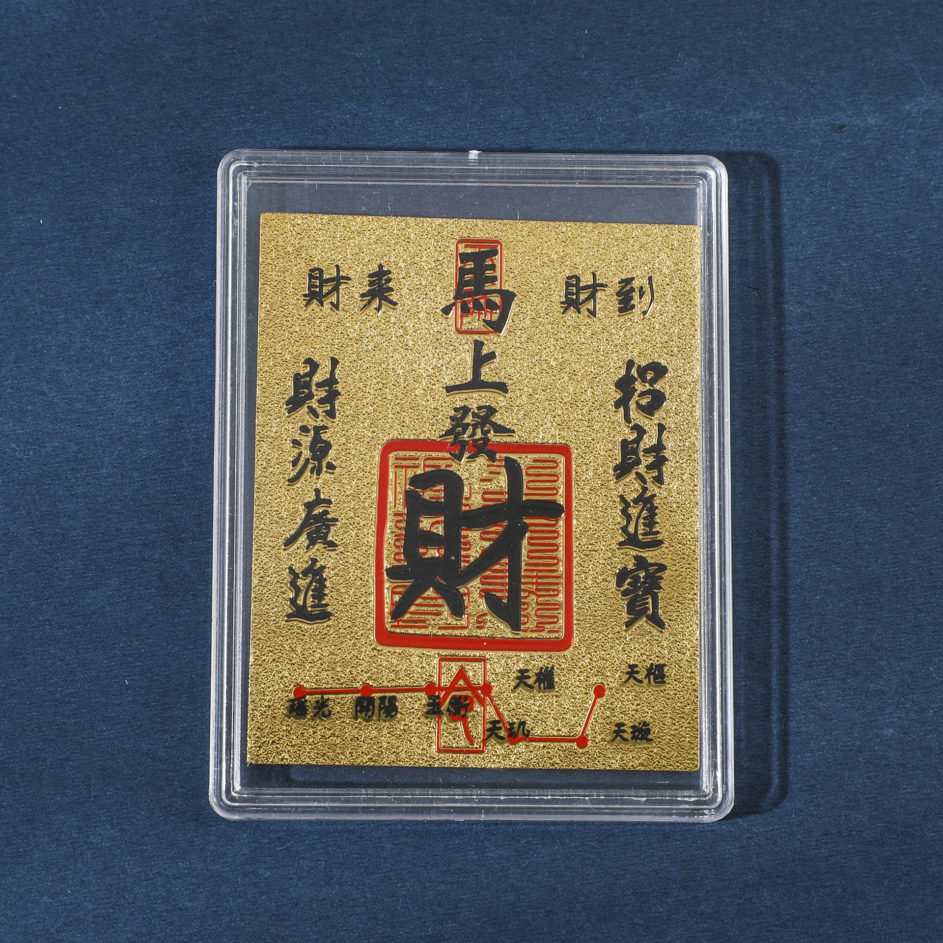 Gold Instant Wealth fortune sticker in clear display case on blue background