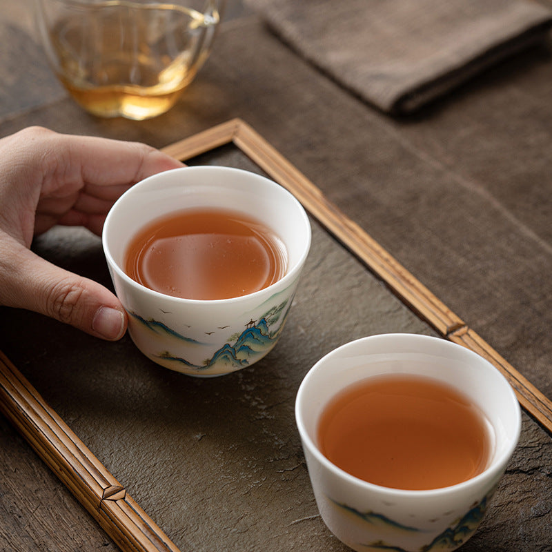 Ceramic Kung Fu Tea Cup – held aloft with matching gaiwan and tea set, mountain scene, linen cloth, lifestyle