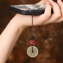 Cinnabar Bagua Mountain Ghost phone charm with red lion head bead and bronze coin, attached to smartphone