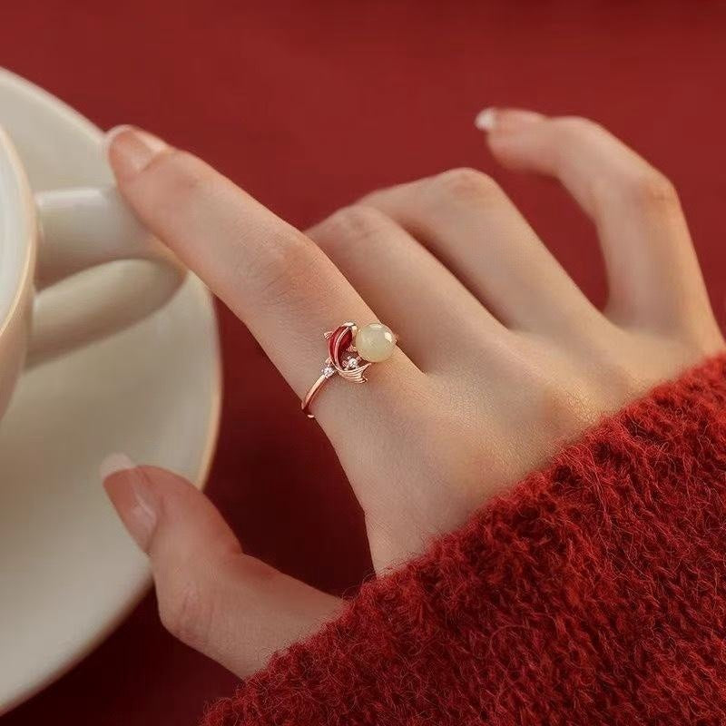 Koi Jade Ring – worn on finger with red knit sweater, holding white teacup, red background, 18K gold feng shui luck ring