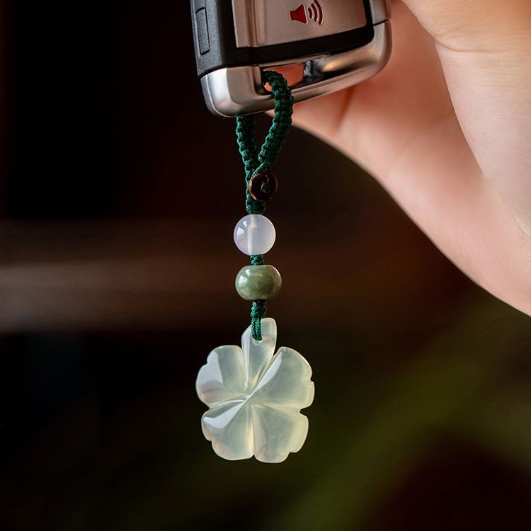 Jade Clover Keychain – clover charm hanging from car key, hand holding against dark background