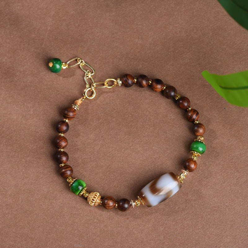 Dzi Rosewood Bracelet – Circular view of rosewood bracelet with gold clasp and dzi bead, Tibetan spiritual jewelry