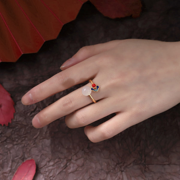 Hetian Jade Clouds Ring – worn on finger surrounded by red autumn leaves on dark textured ground, adjustable ring