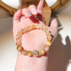Natural Citrine Bracelet – golden yellow and clear citrine beads with gold filigree spacer beads resting on a woman's palm, warm vanity mirror background, lifestyle detail shot