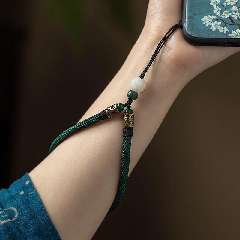 Lotus Bodhi Lanyard – Green lanyard wrapped around wrist holding floral phone case, lifestyle wear shot, bodhi protection charm