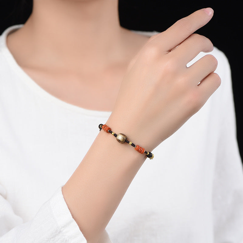 Cotton Cord Bracelet – worn on wrist with white blouse, gold barrel charm and orange beads visible, spiritual jewelry