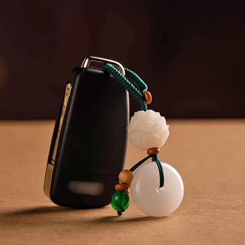 Chalcedony Lotus Keychain – lotus peace buckle attached to black car key standing on brown surface, car feng shui
