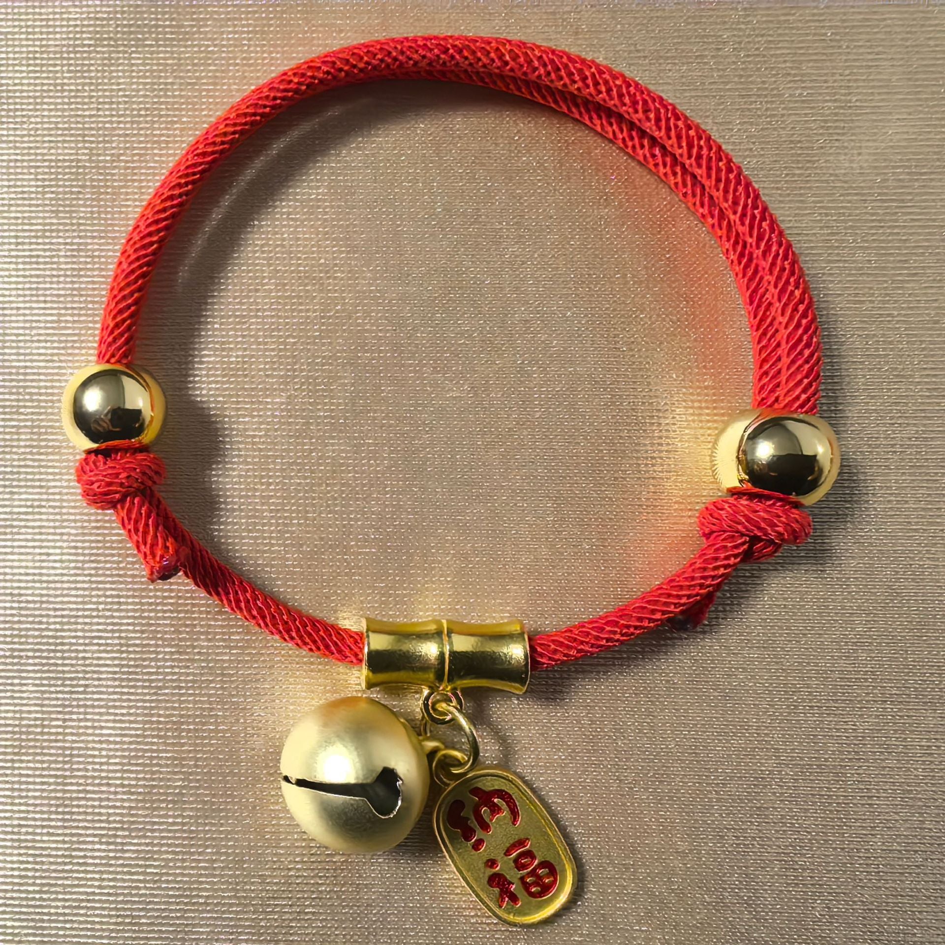 Feng Shui Bell Collar - Red cord with gold bell and Na Fu tag on neutral background, feng shui breakaway pet collar
