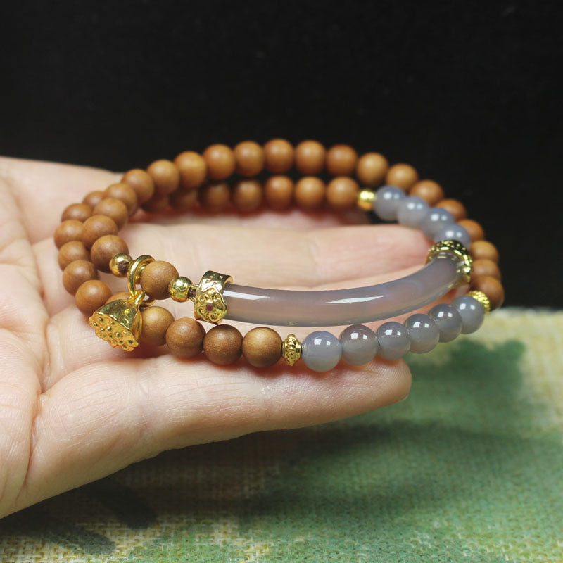 Sandalwood Agate Bracelet – Sandalwood and gray agate beads with gold accents on palm with green element, wellness