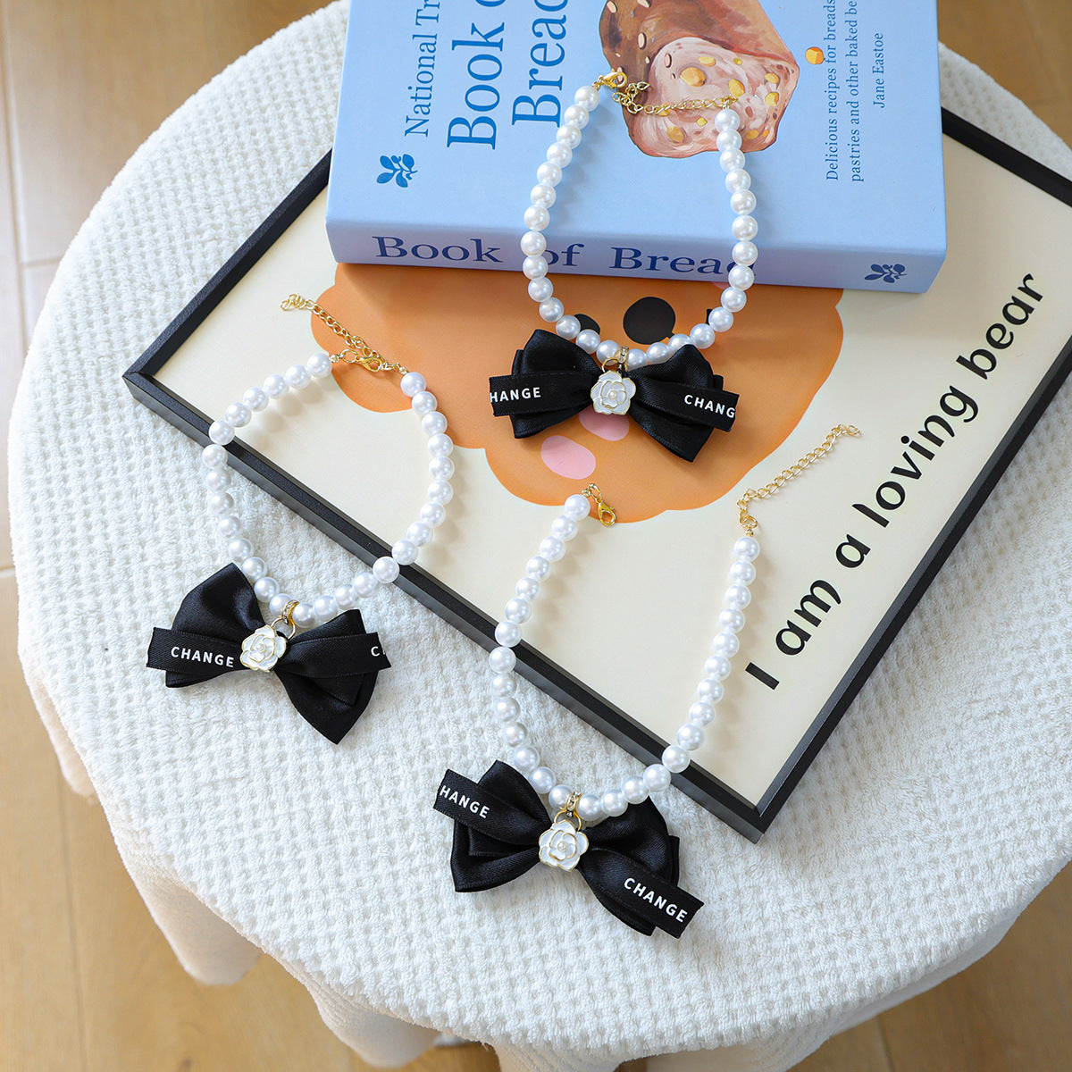 Luxury Crystal Pet Necklace – three pearl collars with black satin bows and white roses, lifestyle styling props