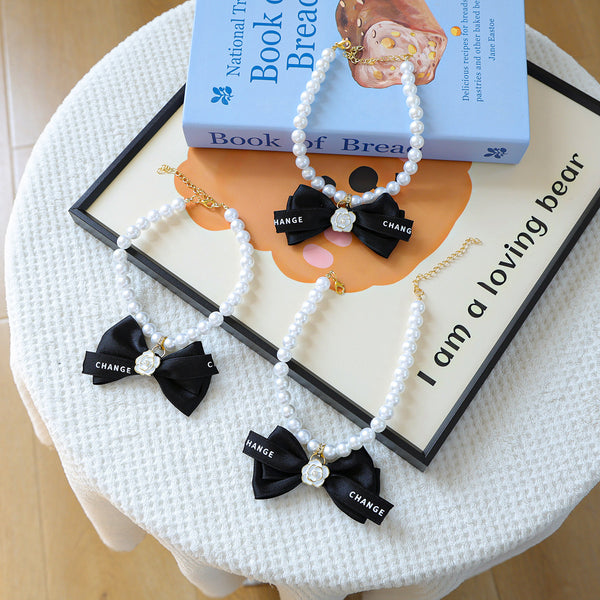 Luxury Crystal Pet Necklace – three pearl collars with black satin bows and white roses, lifestyle styling props