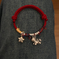 Horse Red String Bracelet – Red string bracelet with silver horse charm lying on dark denim fabric, couple